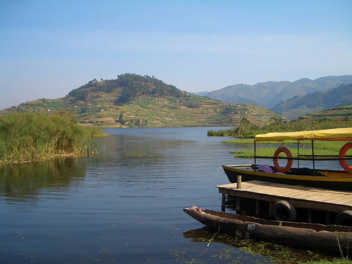 Calm water below green hills near Bwindi