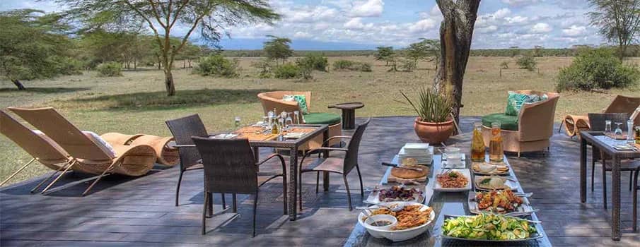 Breakfast table and loungers arranged on a safari lodge deck